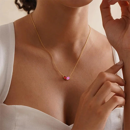 Two pear-shaped stones set together as one heart on a gold-color chain, worn at the collarbone